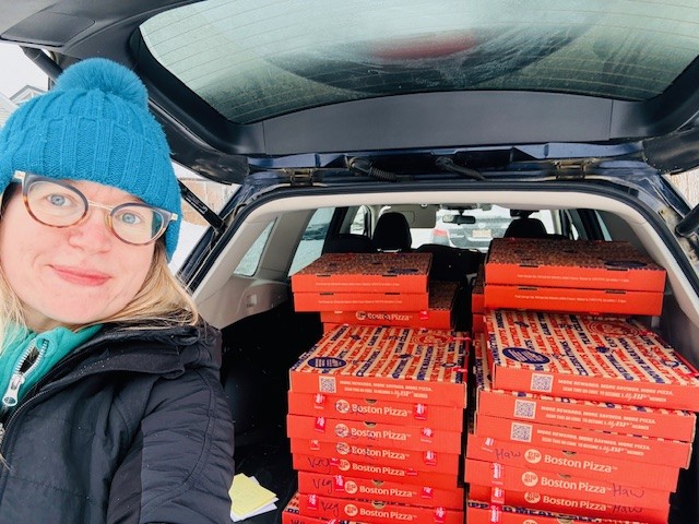 Emily taking a selfie of her and a stack of pizza boxes in the back of a trunk
